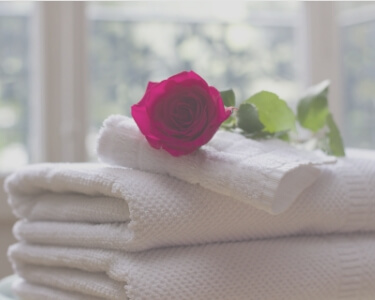 投稿記事のイメージ写真。白い畳んだバスタオルの上に白い畳んだタオルが置かれ、その上にピンクの薔薇の花が置かれています。