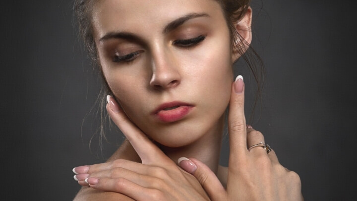 洗練されたワンランク上の女性のイメージ写真。右下を向きながら、優雅な仕草で両手を交差させ、手の甲を顎に添える女性の姿が写っています。
