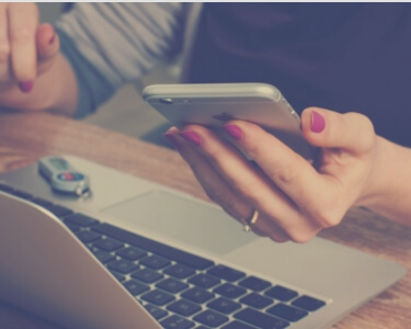 RESERVEのイメージ写真。机に置かれた開いたシルバーのパソコンと、机の椅子に座った人の左手に持ったシルバーのiPhone