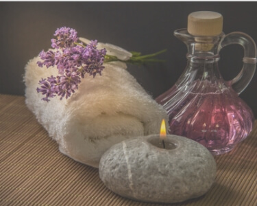 VALENTINE ROSE 渋谷店のイメージ写真。ふわふわの白いタオル、キャンドルの灯り、ピンクのフレグランスボトルが写っています。