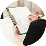 カウンセリングのセッション中の後ろ姿、黒いバインダーに白い紙に白いペンでメモを取っている人